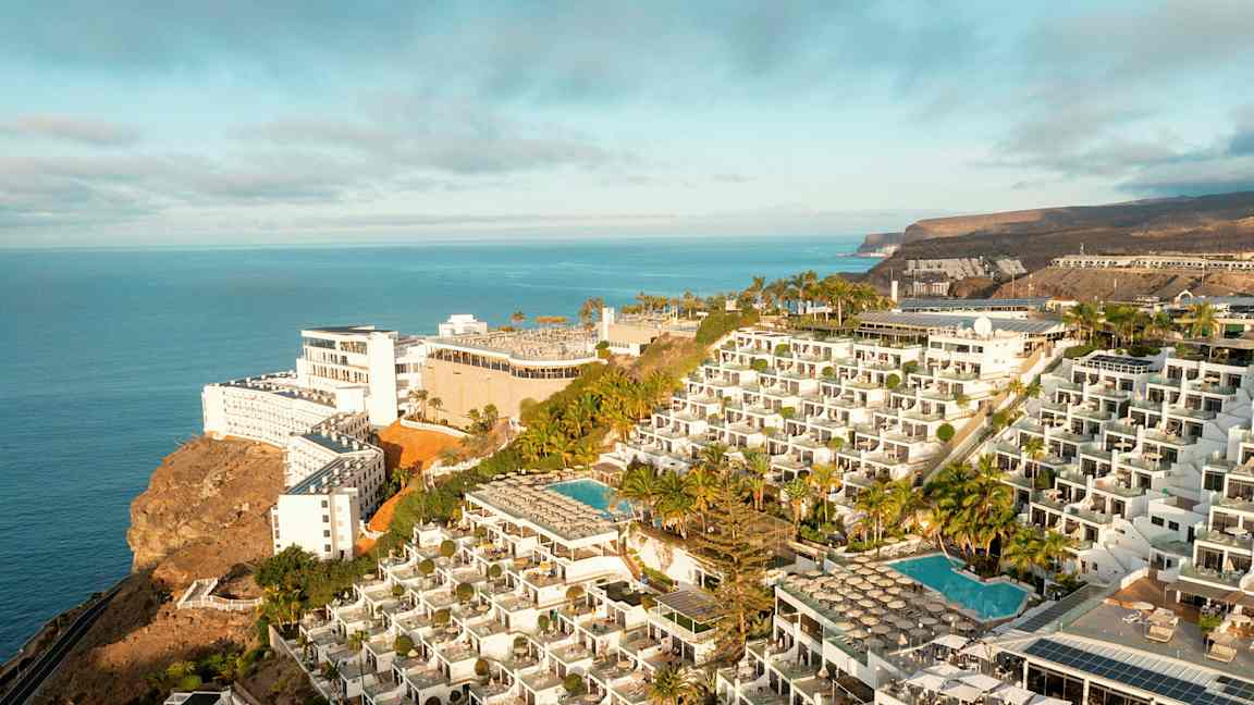 Hotelkompleks på en klippe med swimmingpools og havudsigt. (AI-genereret tekst)