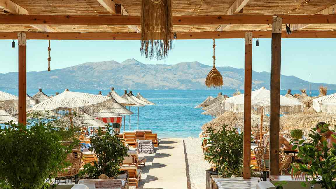 Strandudsigt med parasoller, liggestole og havet i baggrunden. (AI-genereret tekst)