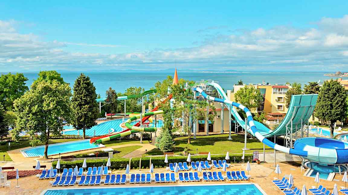 En vandland ved havet med vandrutsjebaner og pools omgivet af liggestole og parasoller. (AI-genereret tekst)