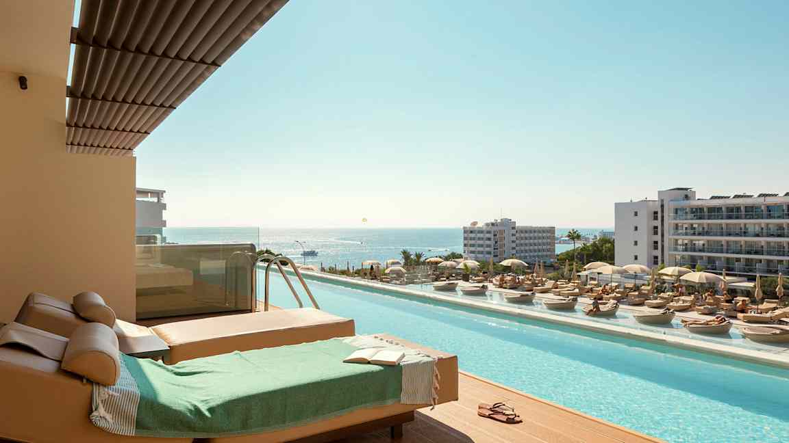 Liggestole og pool med udsigt over havet i en feriested. (AI-genereret tekst)