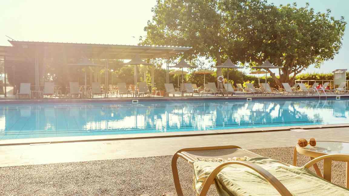 En liggestol og et bord ved kanten af en swimmingpool. (AI-genereret tekst)