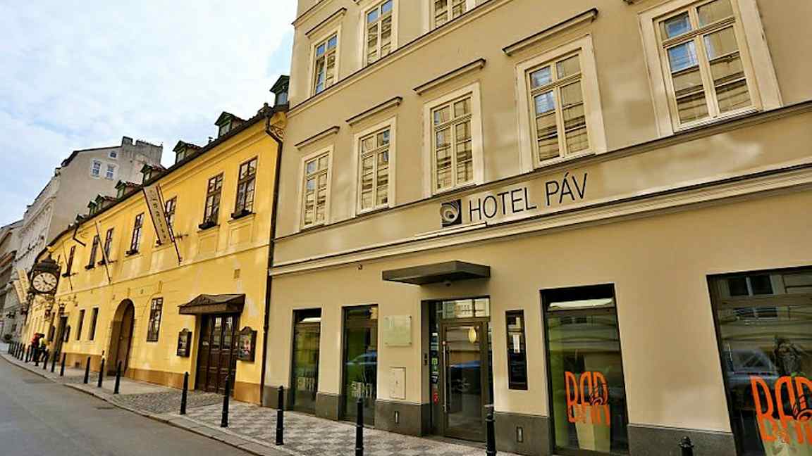 Bygning i bymiljø med et hotel kaldet Hotel Páv. (AI-genereret tekst)