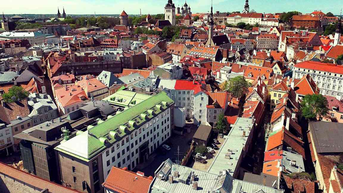 Luftfoto af en by med ældre bygninger i forskellige farver. (AI-genereret tekst)