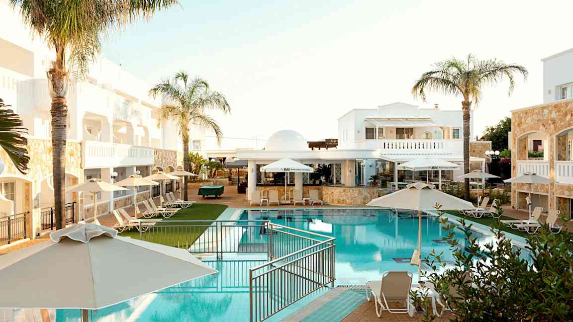 Hotelområde med pool, liggestole og parasoller. (AI-genereret tekst)