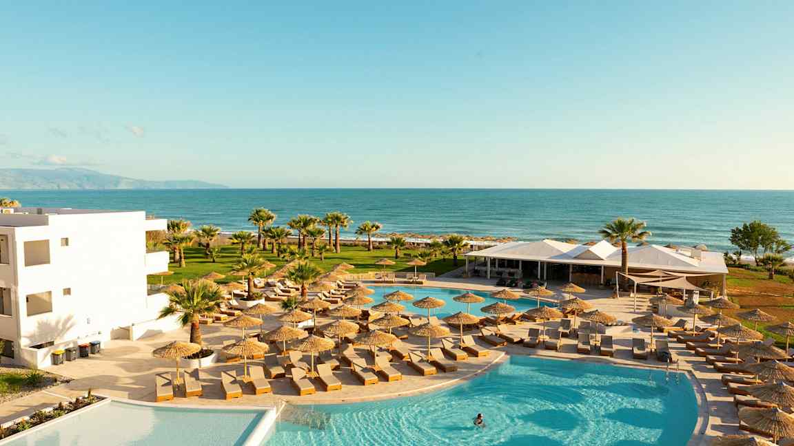 Poolområde med liggestole og parasoller, med udsigt over havet. (AI-genereret tekst)