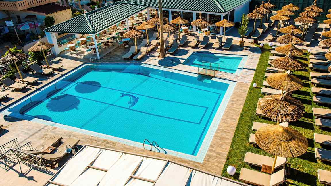 En pool med liggestole og parasoller ved en udendørs serveringsområde. (AI-genereret tekst)