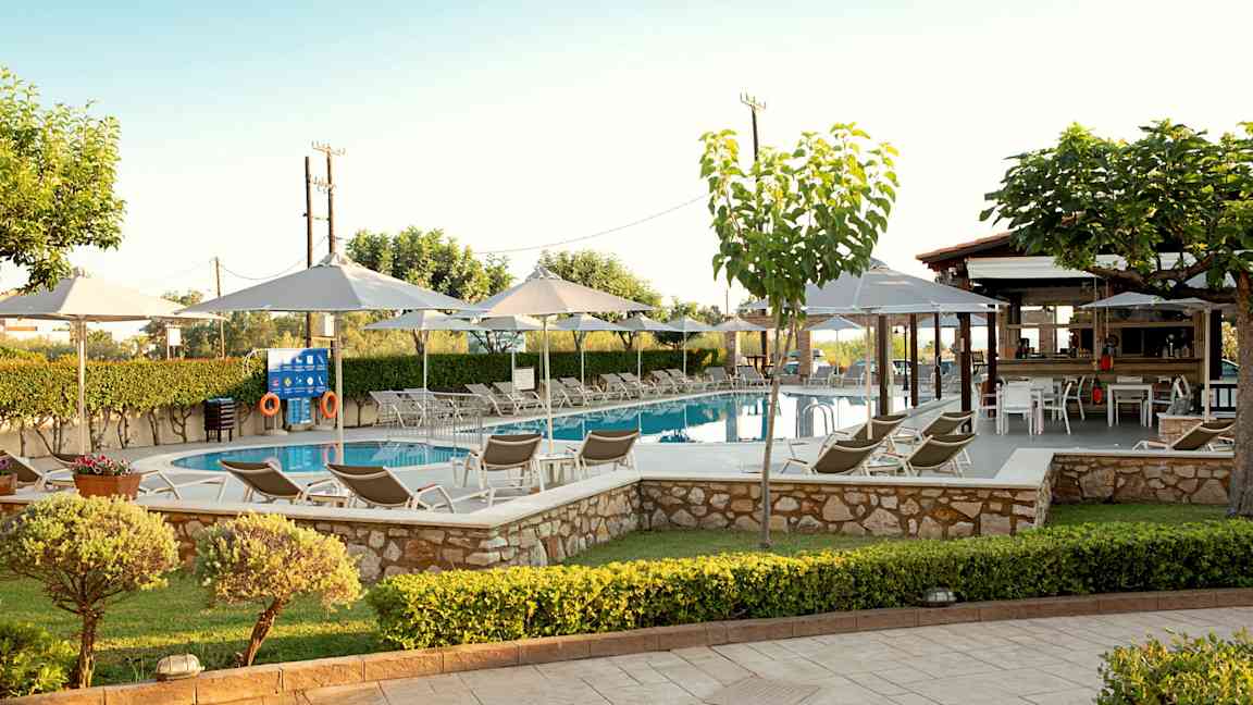 En swimmingpool omgivet af liggestole, parasoller og grønne områder. (AI-genereret tekst)