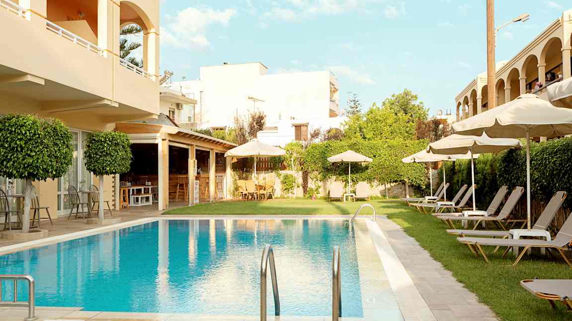 Hotelområde med pool, liggestole og parasoller. (AI-genereret tekst)