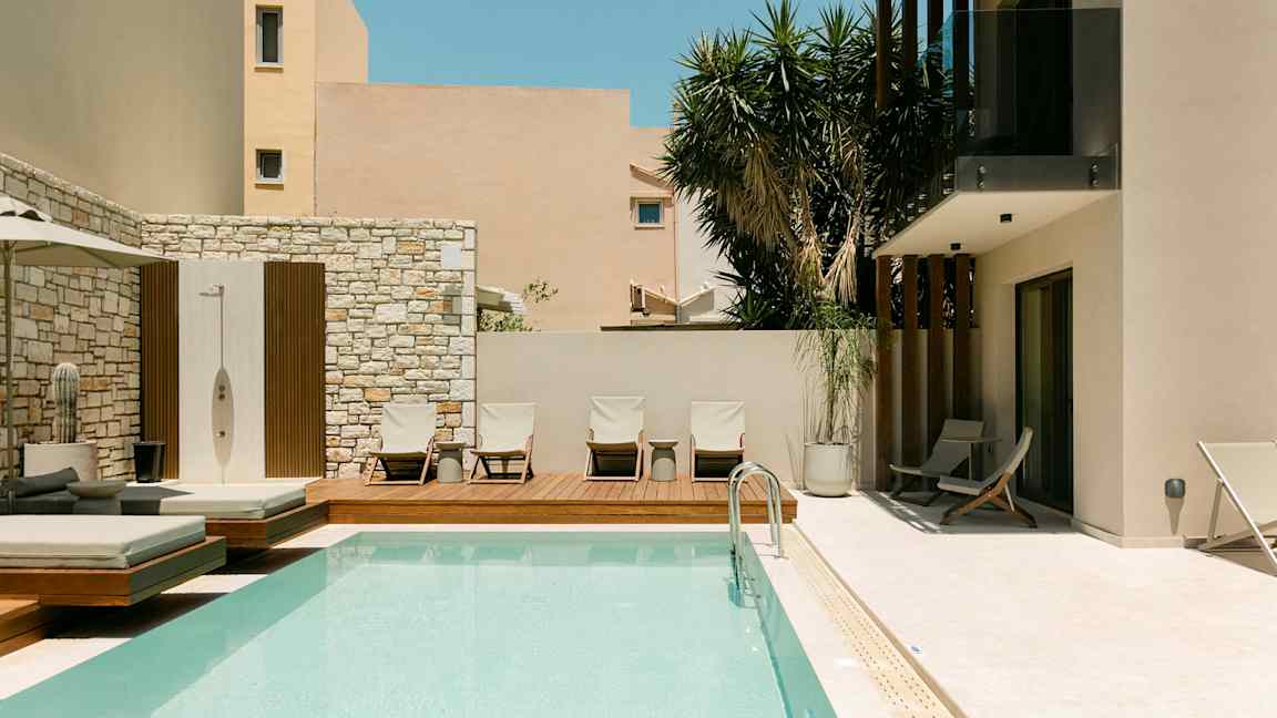 Udendørs pool og liggestole ved en moderne bygning. (AI-genereret tekst)