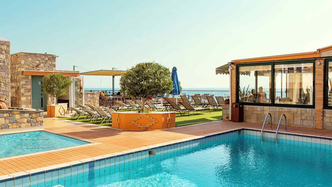 Billede af en udendørs pool ved siden af en solterrasse med solsenge og havudsigt. (AI-genereret tekst)