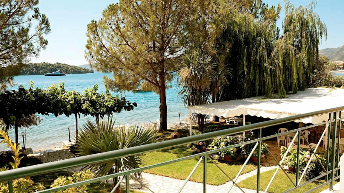 Udsigt over en have med frodige planter, træer og havet i baggrunden. (AI-genereret tekst)