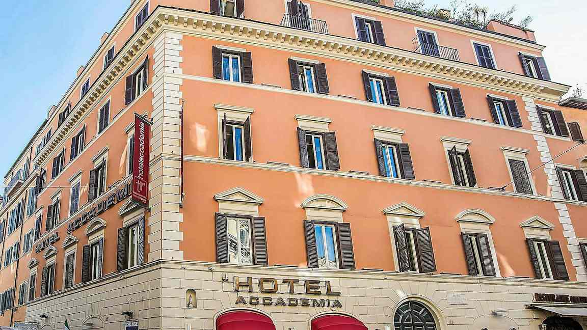 Et hotel i en pastelfarvet bygning med flere etager og mange vinduer. (AI-genereret tekst)