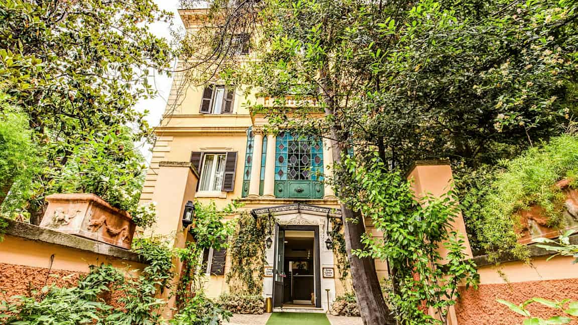 En bygning med en dekorativ indgang omgivet af bevoksning. (AI-genereret tekst)