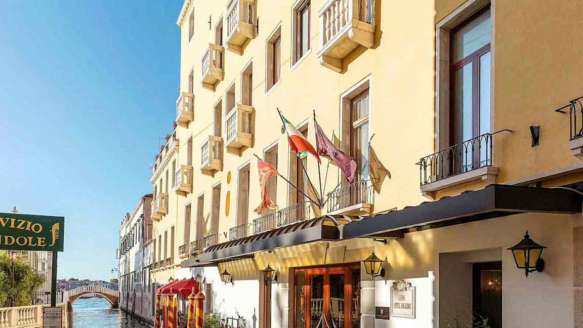 En gul bygning med altaner langs en kanal, med en gangbro i baggrunden. (AI-genereret tekst)