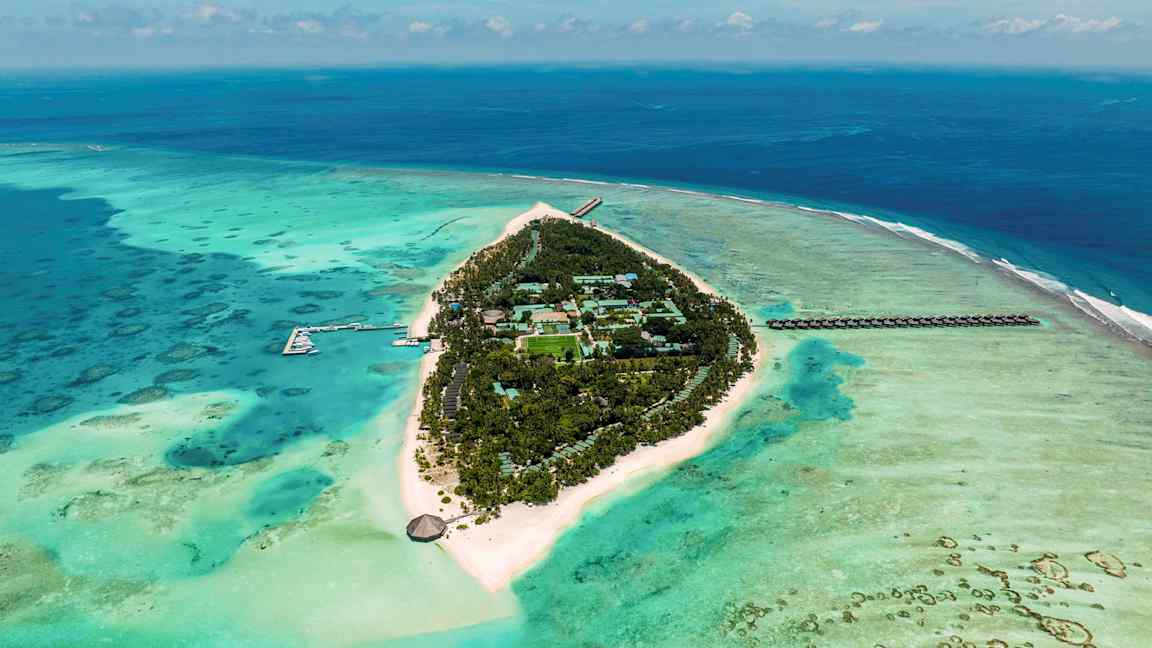 Luftfoto af en tropisk ø omgivet af turkis hav med hvide sandstrande og grøn vegetation. (AI-genereret tekst)