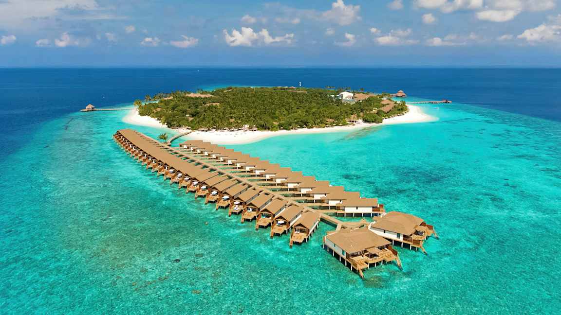 Luftfoto af en tropisk ø med turkis vand, hvide sandstrande og bungalows på pæle over havet. (AI-genereret tekst)