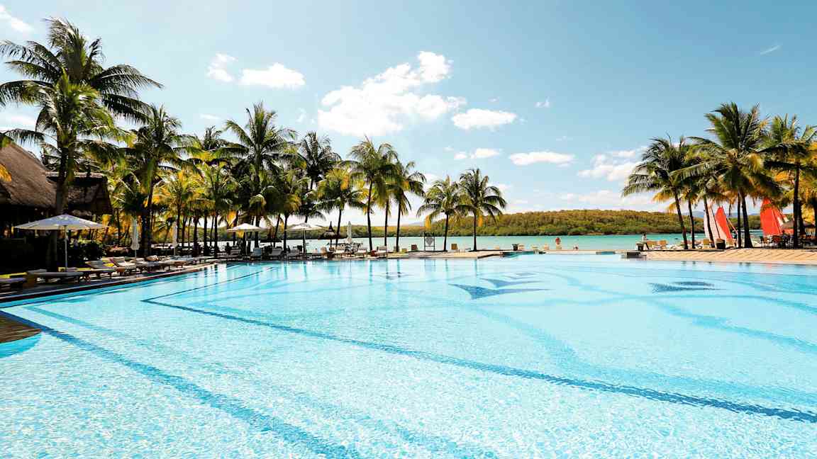 Stor pool ved havet omgivet af palmer. (AI-genereret tekst)