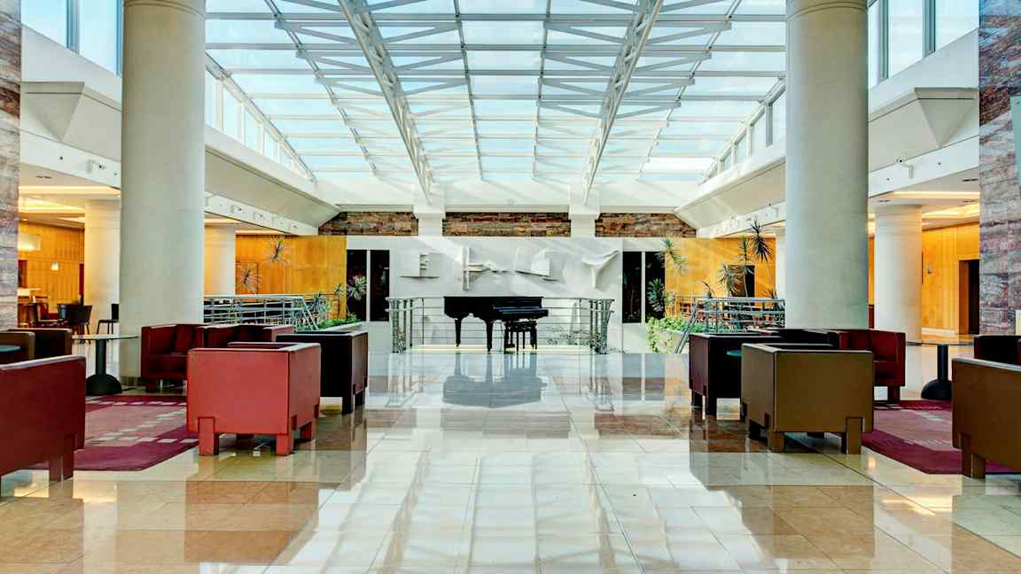 Lys og rummelig hotellobby med siddegrupper og et flygel. (AI-genereret tekst)