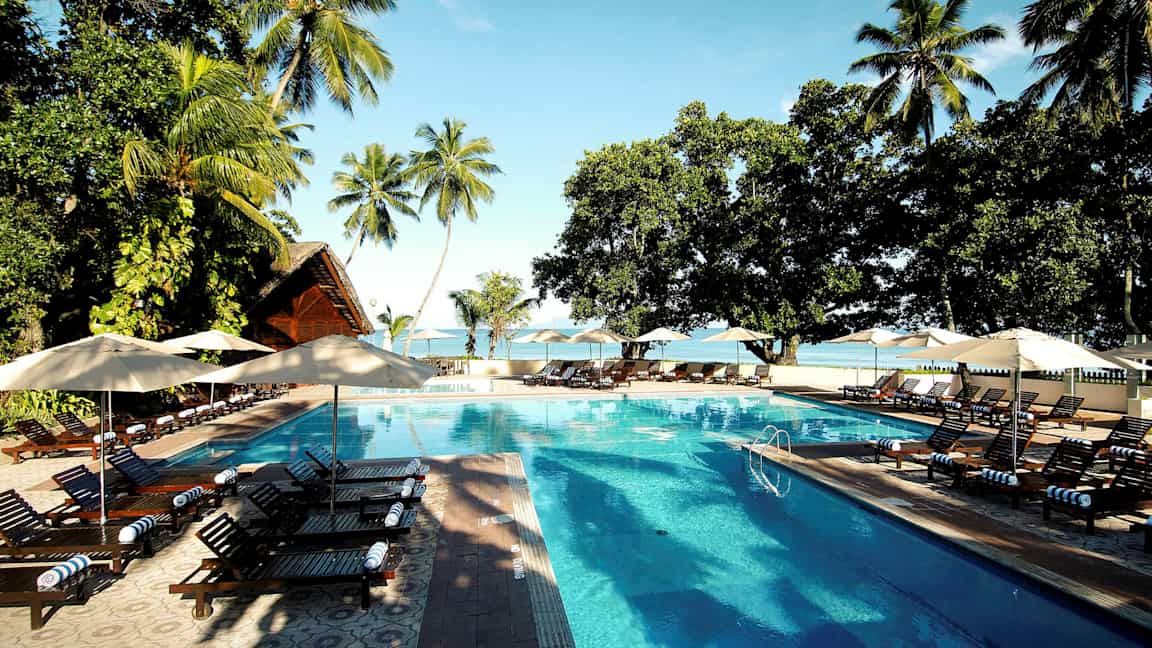 En pool med solsenge på et tropisk ferieområde. (AI-genereret tekst)