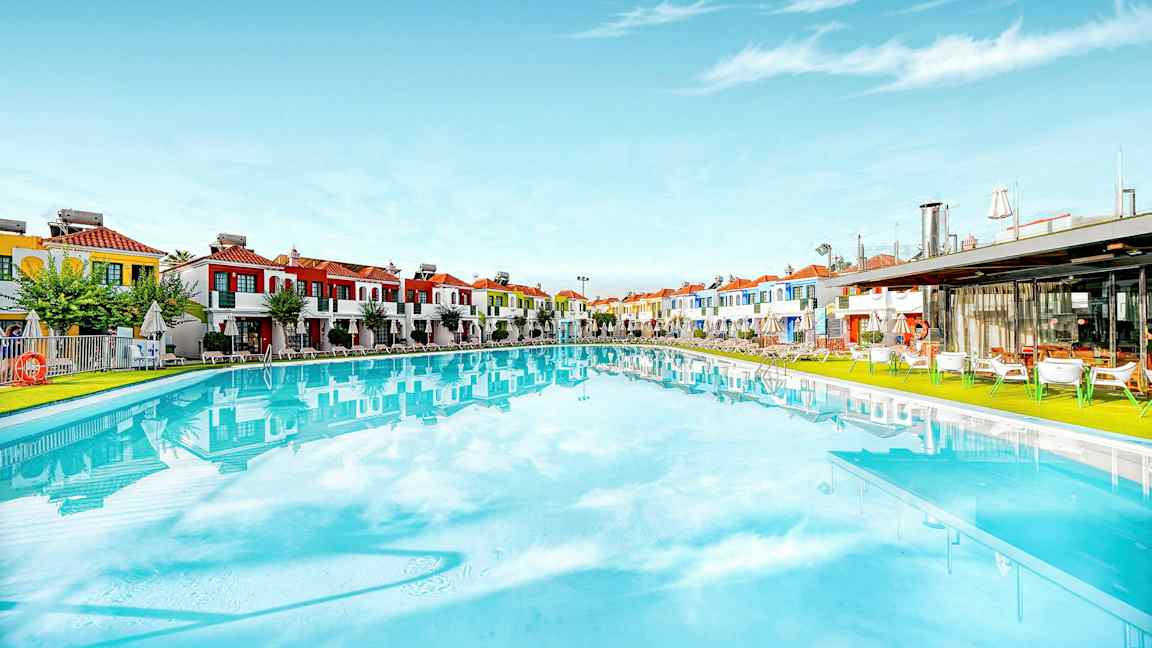Stor pool med farverige bygninger i baggrunden. (AI-genereret tekst)