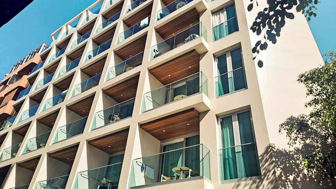 En bygning med altaner og glasrækværk. (AI-genereret tekst)