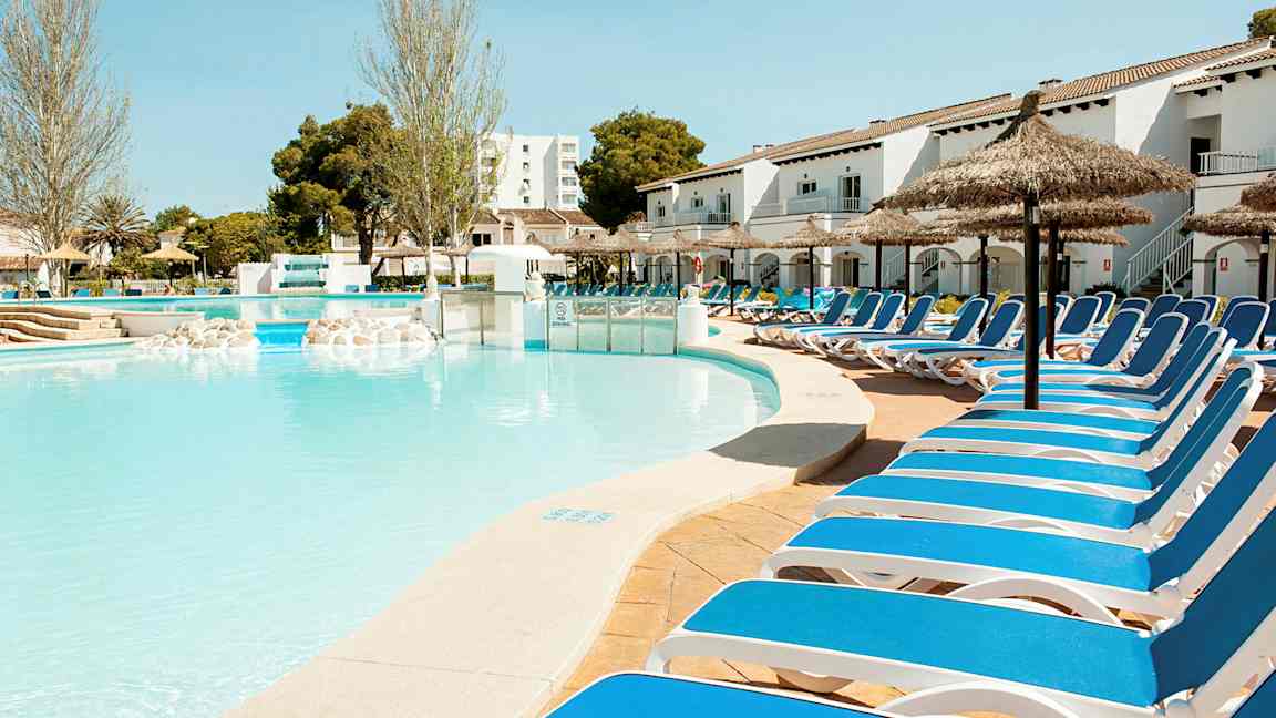 En udendørs pool med liggestole langs kanten under solrige forhold. (AI-genereret tekst)