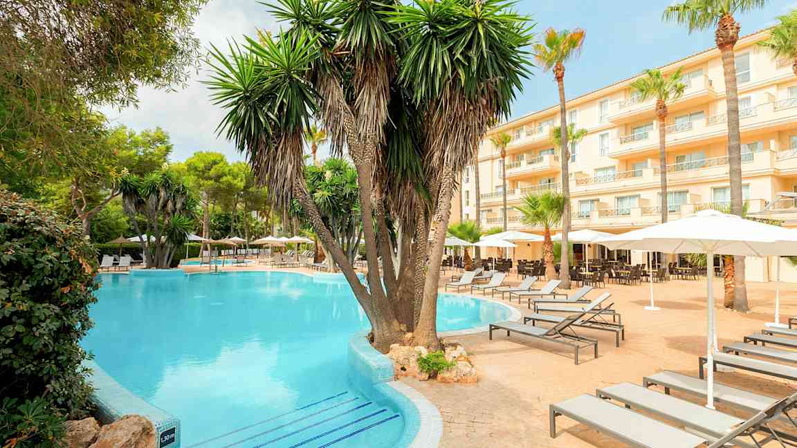 Hotelområde med pool, palmer og solvogne. (AI-genereret tekst)