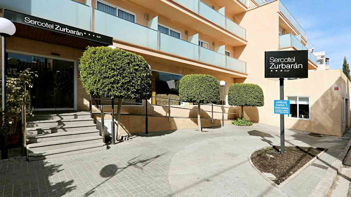 Billede af indgangen til hotellet Sercotel Zurbarán med træer og altaner. (AI-genereret tekst)
