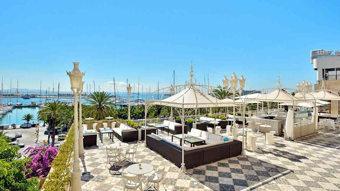 En rummelig terrasse med siddeområder, parasoller og havudsigt. (AI-genereret tekst)