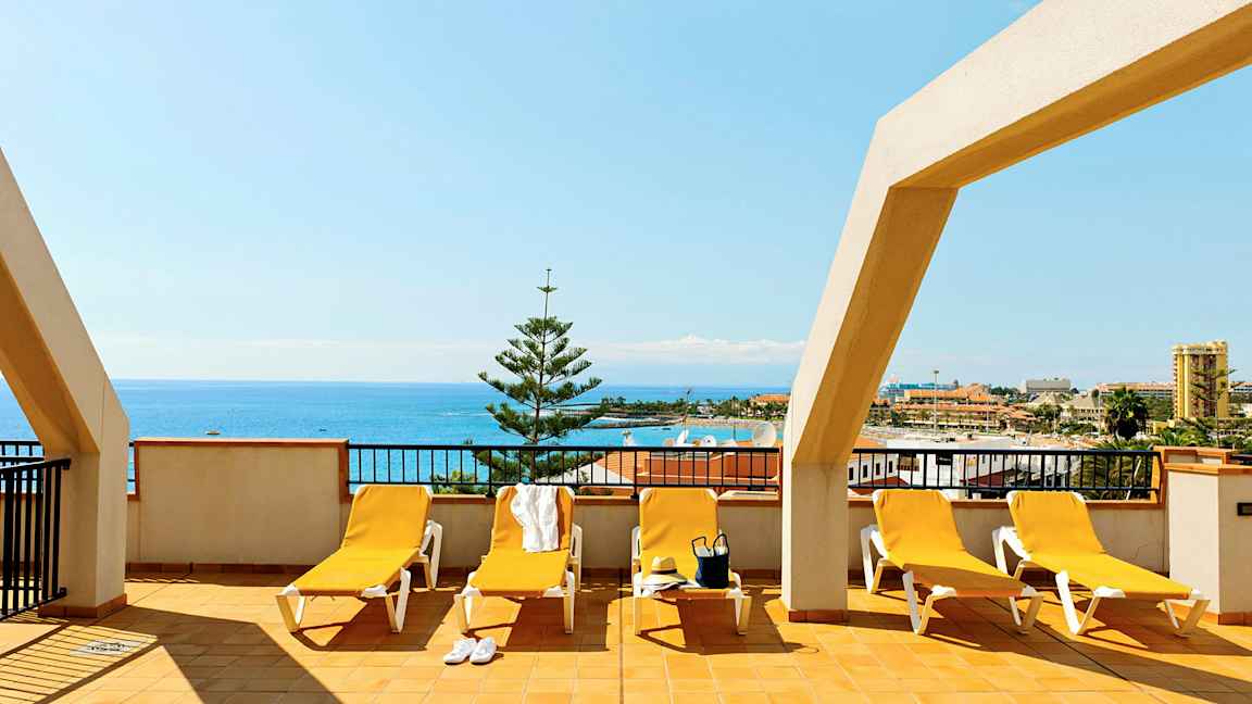 Terrasse med liggestole og havudsigt. (AI-genereret tekst)