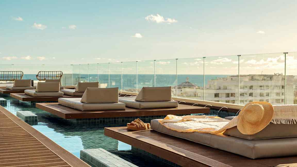 Liggepladser ved en pool med udsigt over byen og havet. (AI-genereret tekst)
