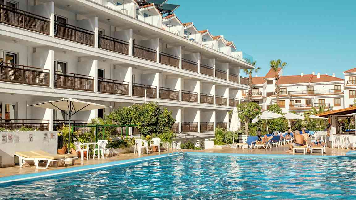 Hotelbygning ved en swimmingpool. (AI-genereret tekst)