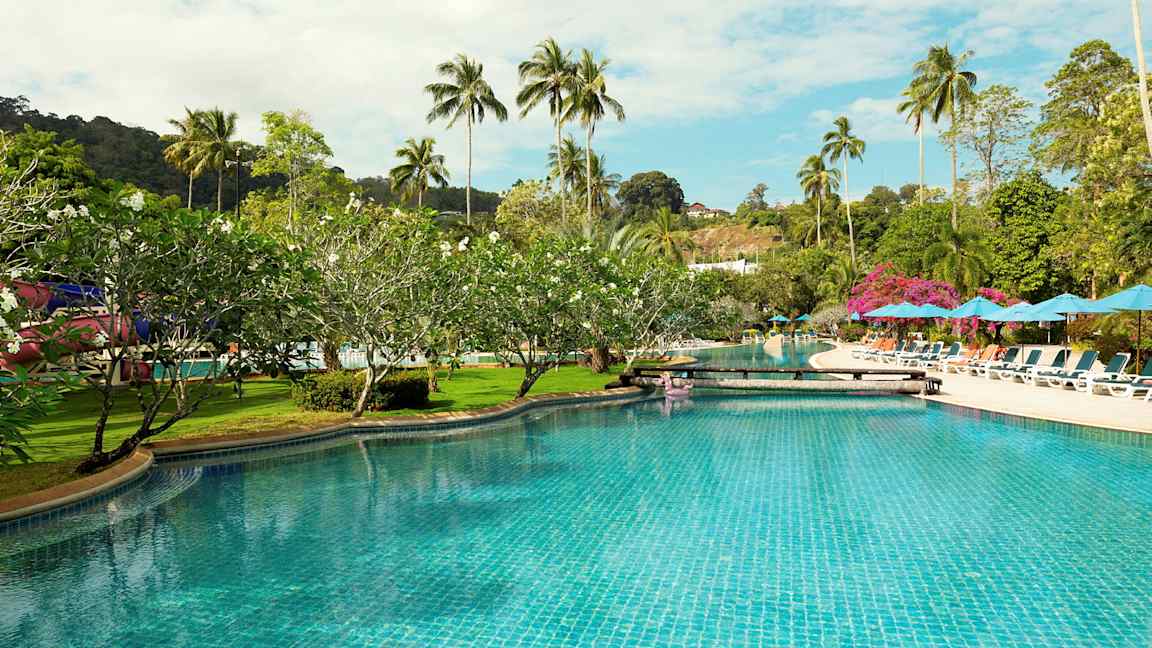 En swimmingpool omgivet af liggestole, parasoller og palmetræer. (AI-genereret tekst)