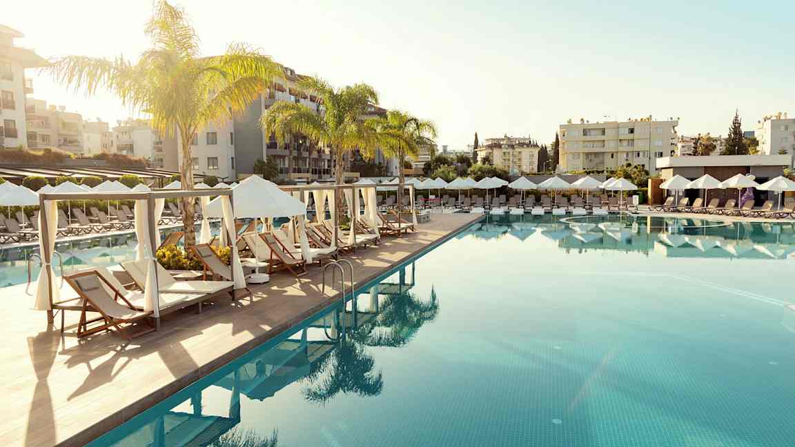 En pool med liggestole og parasoller i en resorts miljø. (AI-genereret tekst)