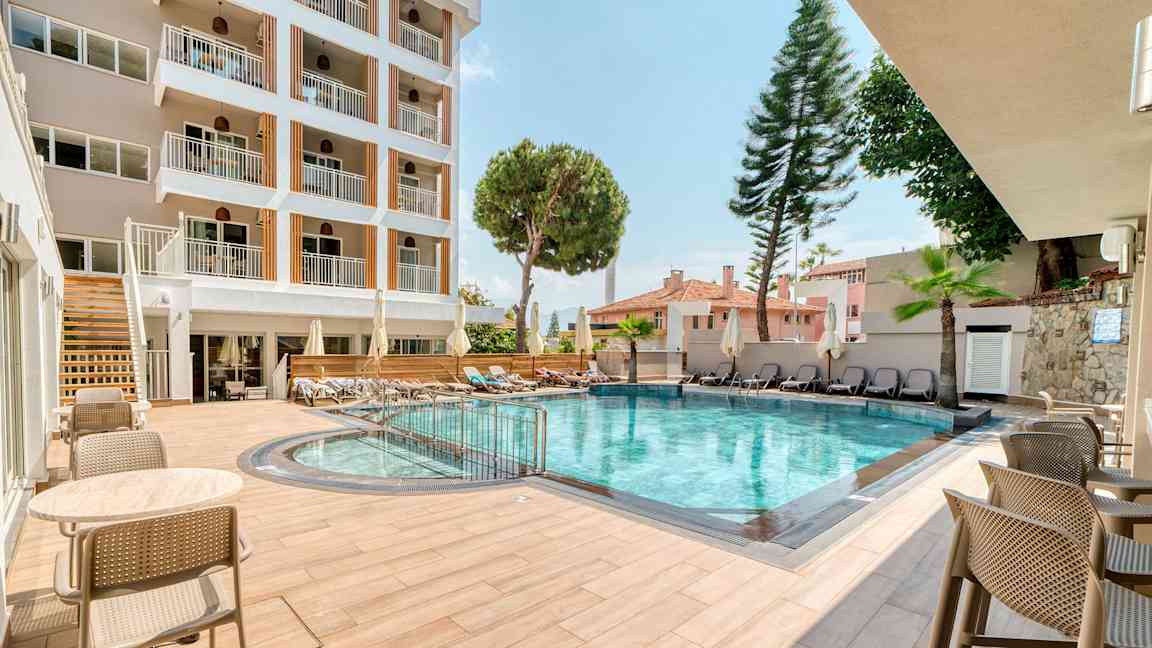 Hotellets udendørs pool med siddepladser og liggestole. (AI-genereret tekst)