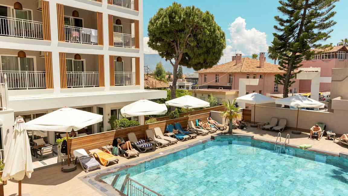 Udendørs pool foran et hotel med liggestole og parasoller. (AI-genereret tekst)