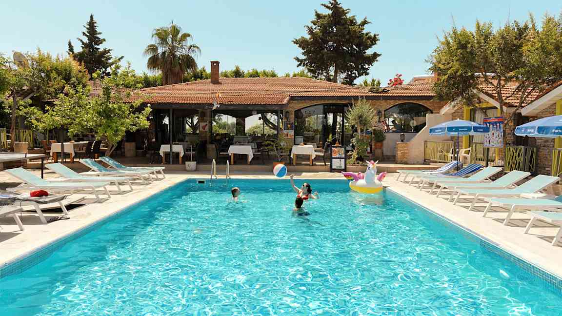 Udendørs swimmingpool med mennesker, der bader ved en feriebolig. (AI-genereret tekst)