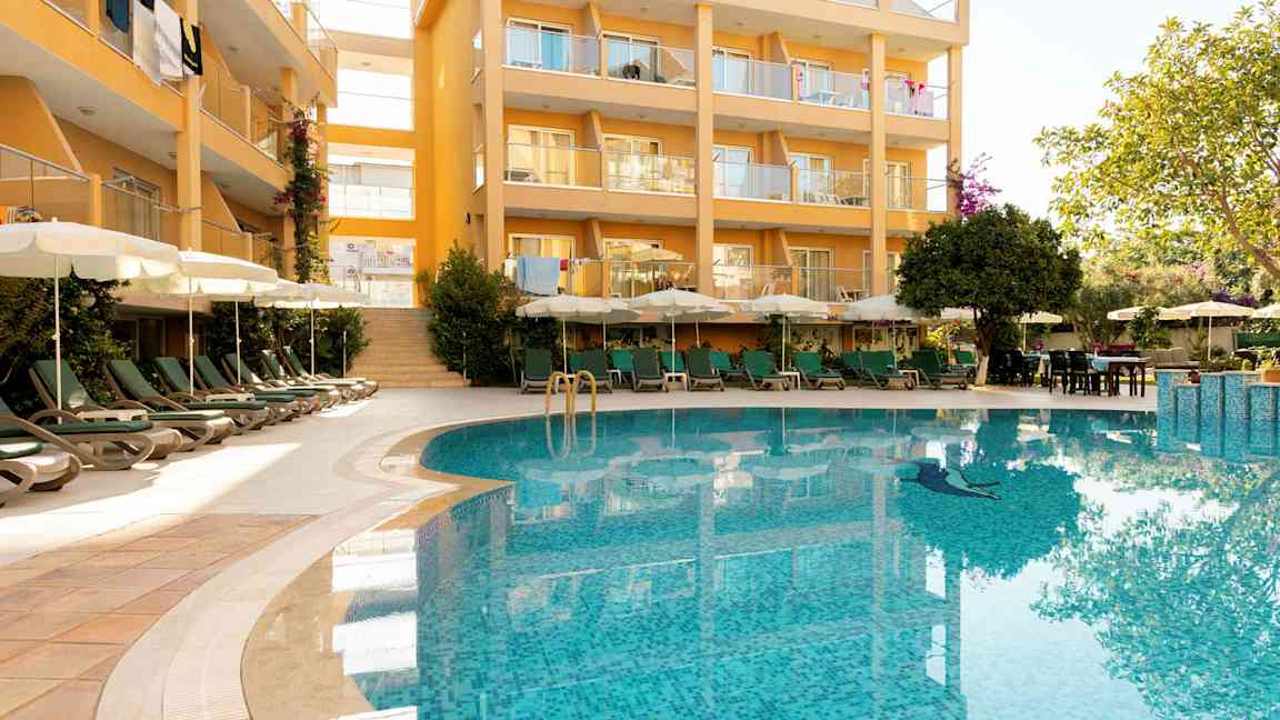 Bygning med altaner og en pool i forgrunden. (AI-genereret tekst)