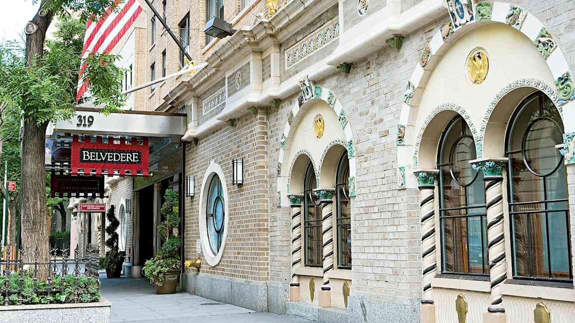Facaden af en bygning med udsmykkede vinduer og en indgang med et rødt skilt, der siger 'Belvedere'. (AI-genereret tekst)