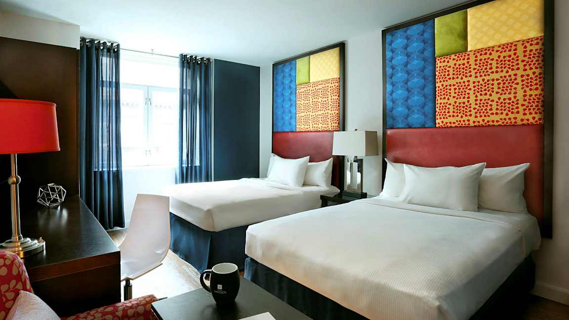 Hotelværelse med to senge, moderne møbler og dekorative elementer. (AI-genereret tekst)