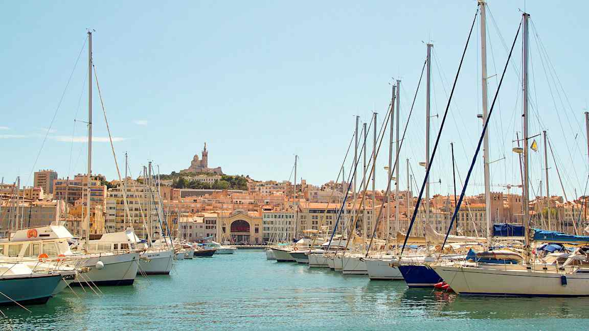 En marina med sejlbåde og en by i baggrunden. (AI-genereret tekst)