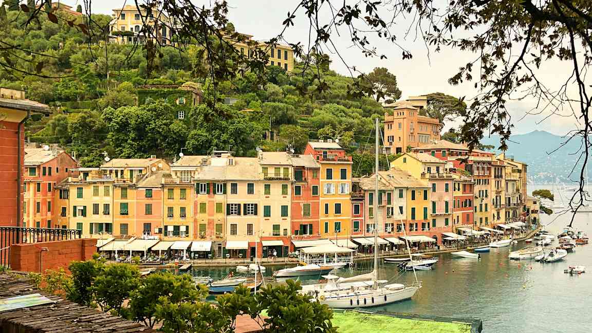 En havn med farverige bygninger og sejlbåde ved vandet. (AI-genereret tekst)