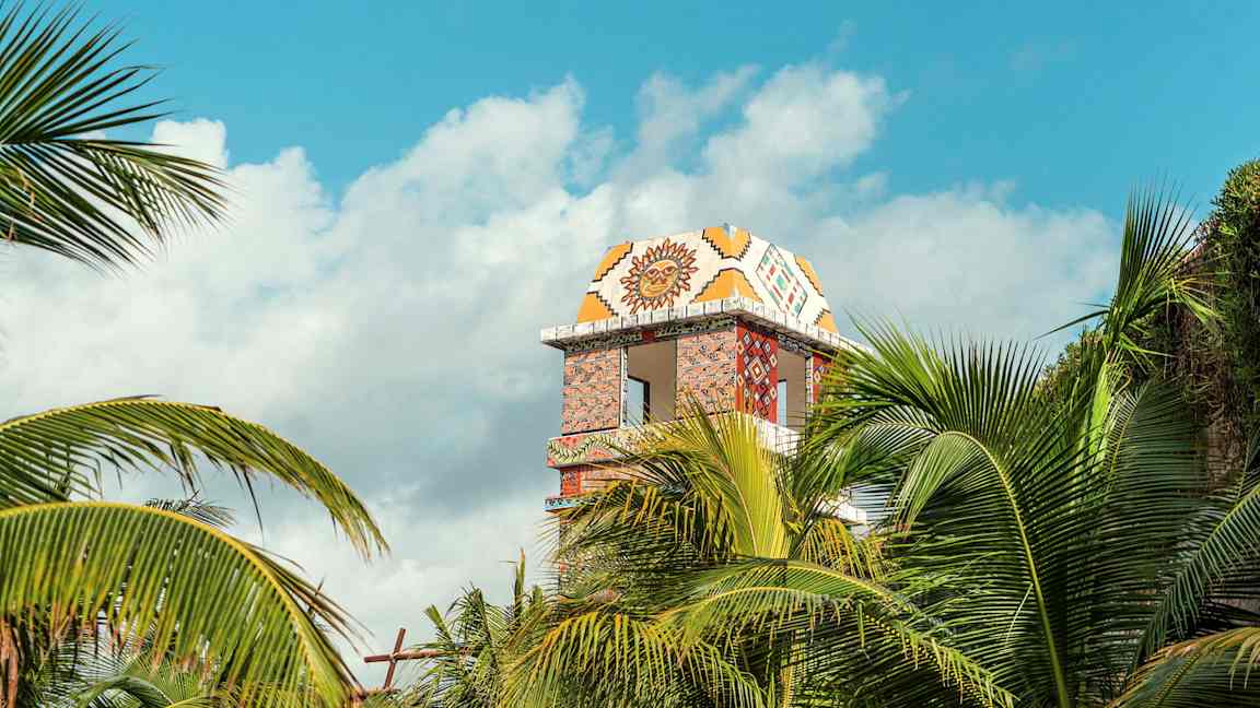 Dekoreret tårnbygning synlig bag palmer. (AI-genereret tekst)