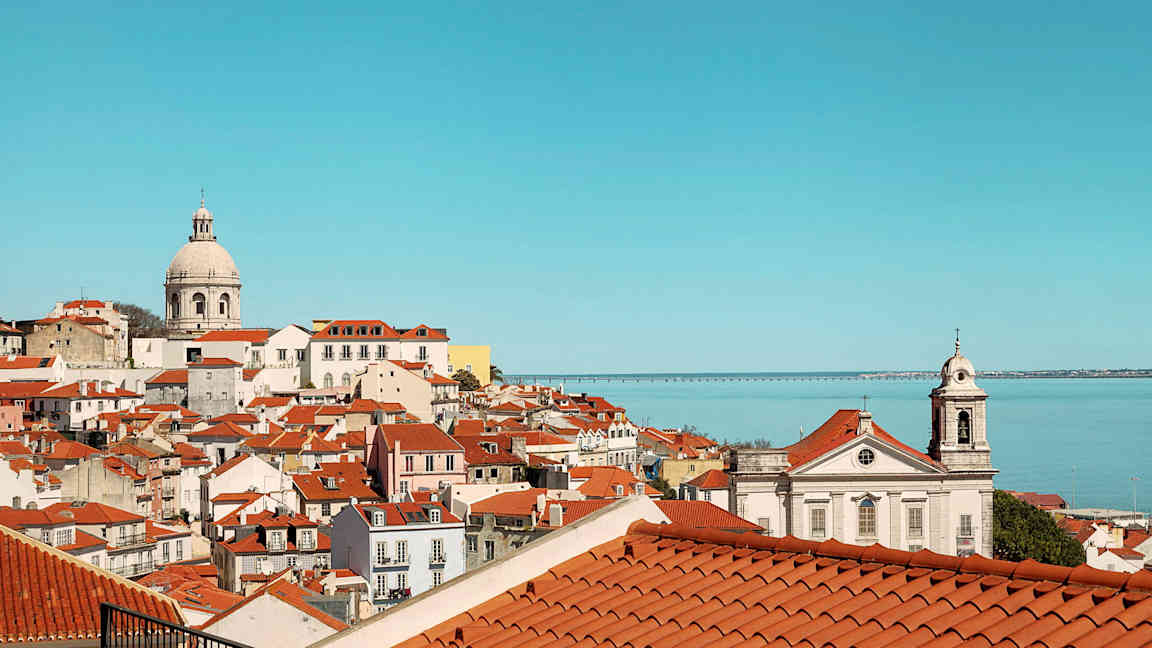 Udsigt over en by med røde tegltage og hav i baggrunden. (AI-genereret tekst)