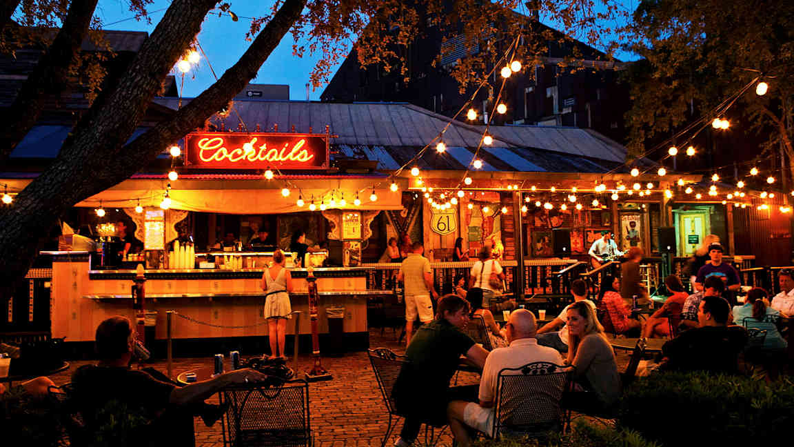 En udendørsbar med belysning og gæster. (AI-genereret tekst)