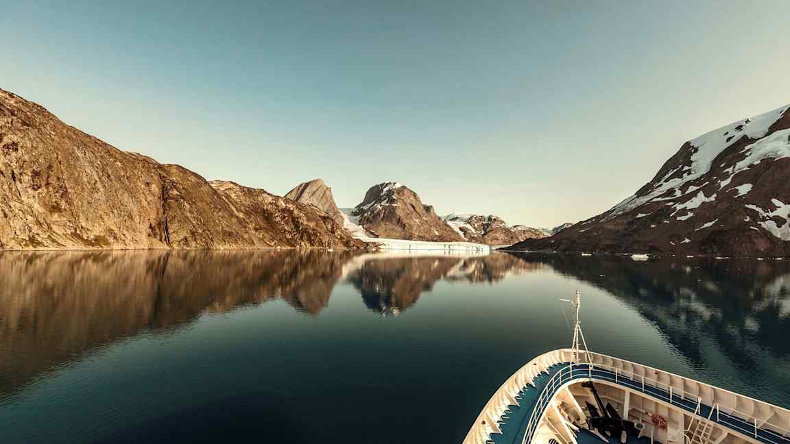 Et skib i en rolig fjord omgivet af bjerge med sne. (AI-genereret tekst)