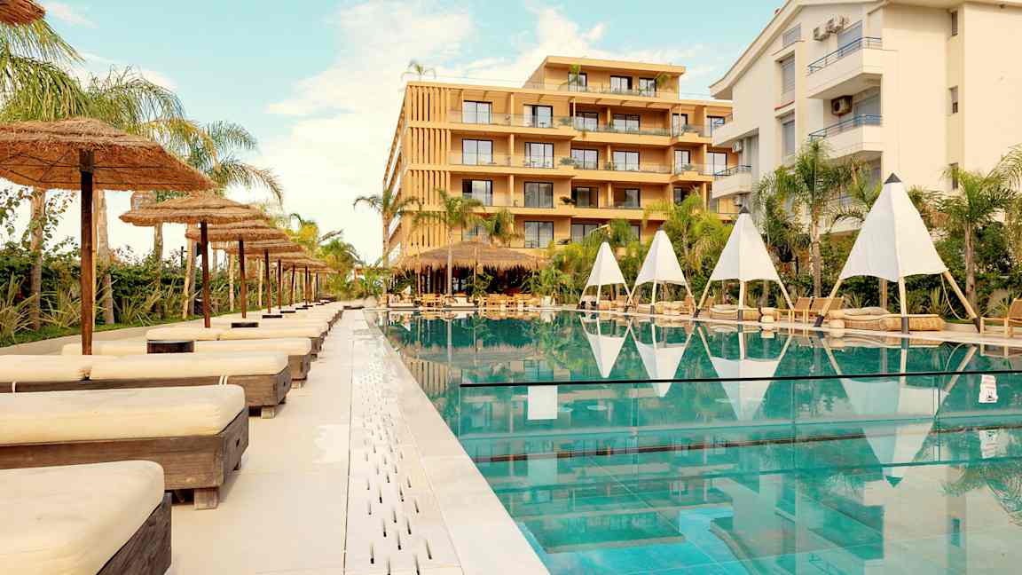 Udendørs swimmingpool med liggestole og parasoller ved et hotel. (AI-genereret tekst)