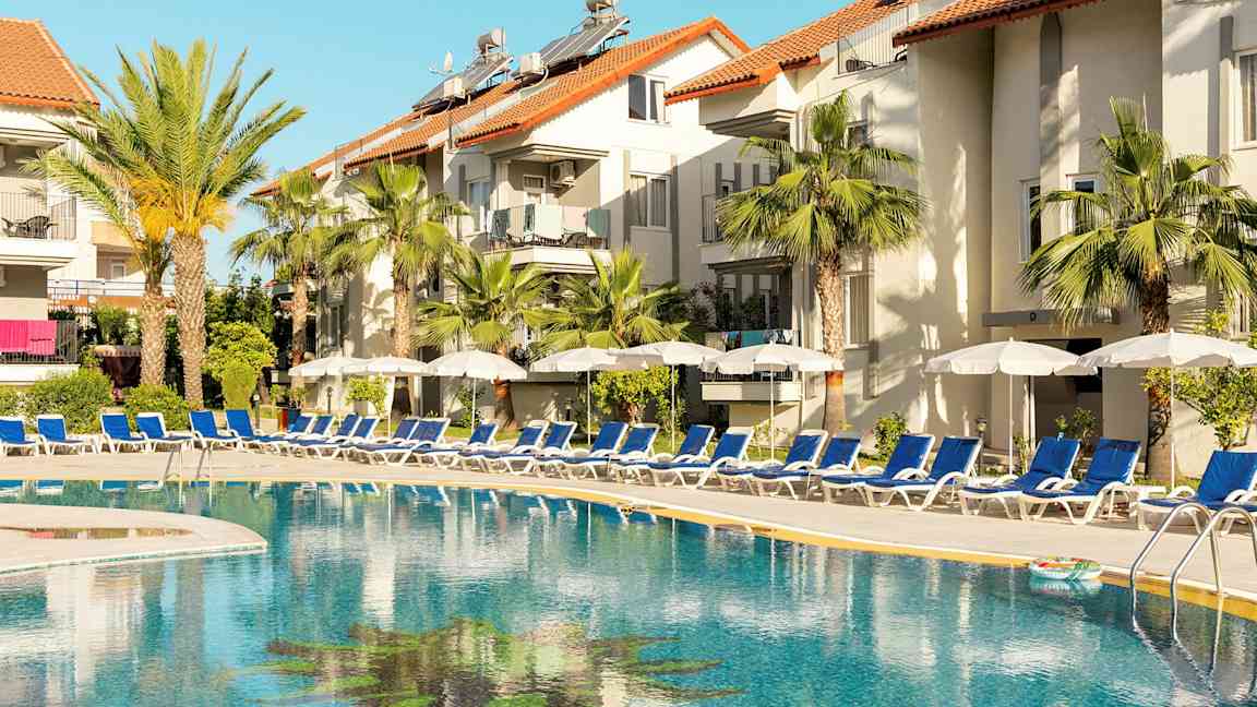 Udendørs pool ved hotel med liggestole og parasoller. (AI-genereret tekst)