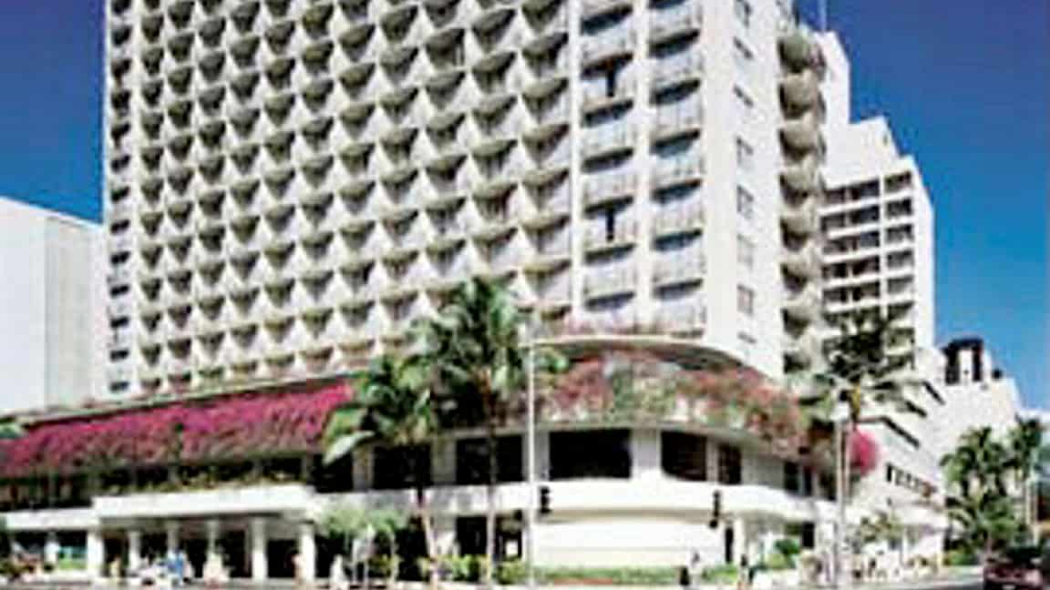 Et billede af en høj hotelbygning med altaner og omkringliggende beplantning. (AI-genereret tekst)