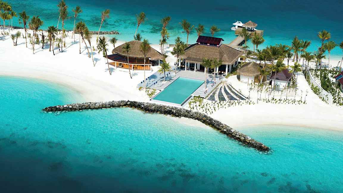 Luftfoto af en tropisk resort ved havet med en pool, hvide strande og palmer. (AI-genereret tekst)